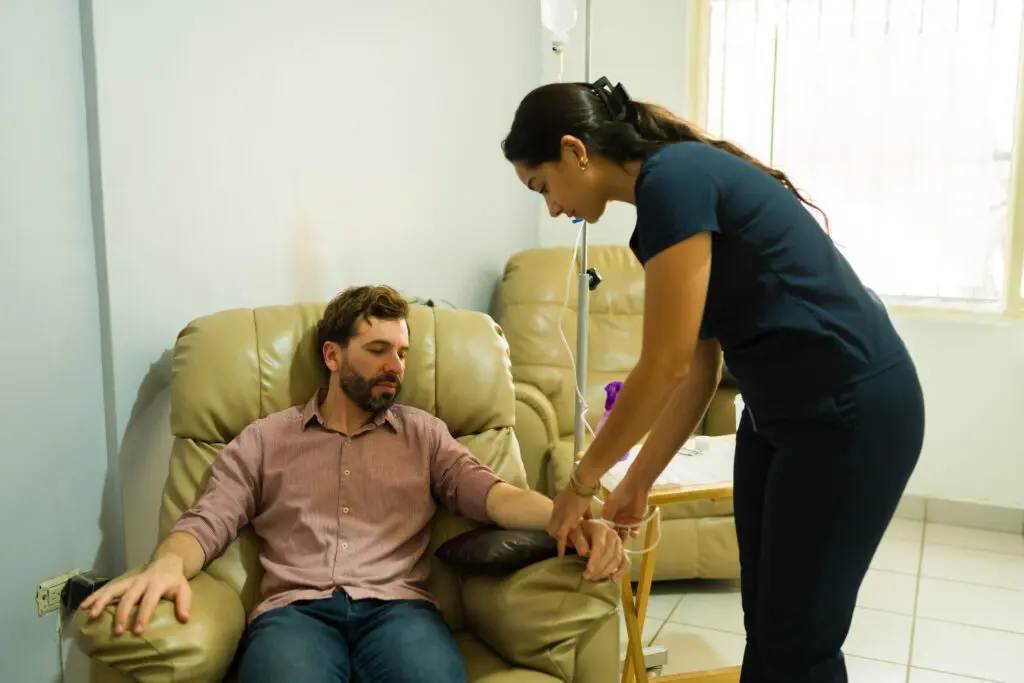 Sick man doing IV drip therapy and getting vitaminized serum