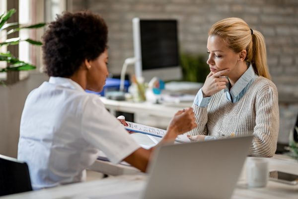 thoughtful-woman-going-through-medical-test-results-with-her-doctor-clinic